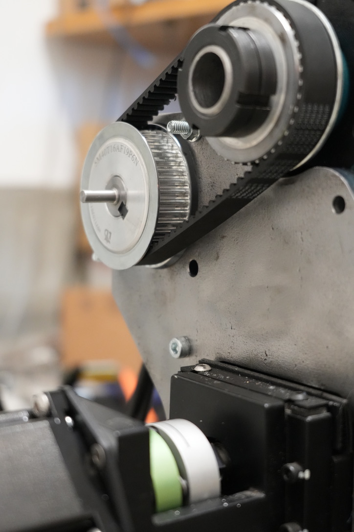 A belt-driven motor and spindle assembly mounted above the lathe slide