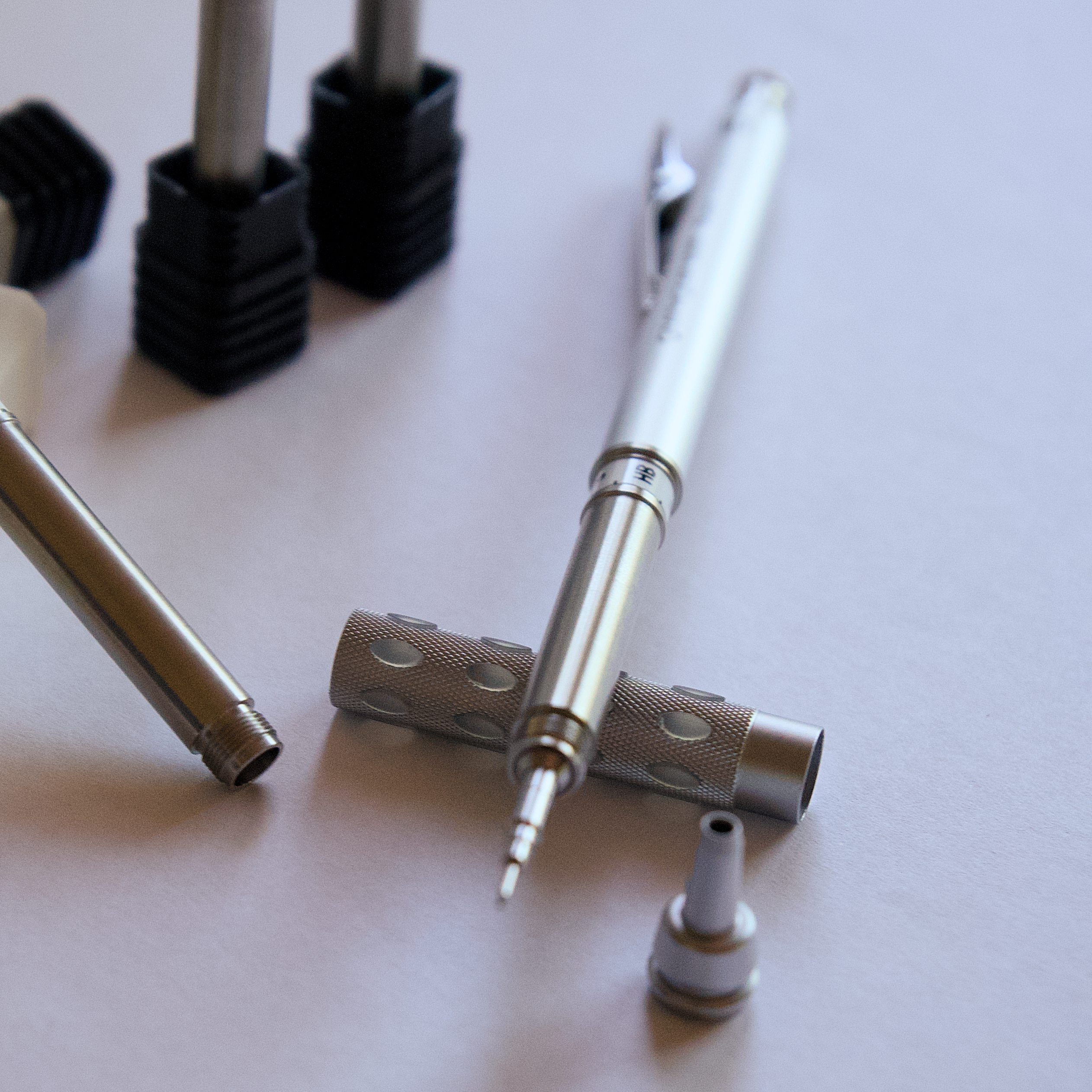 Side view of a stainless mechanical pencil and separate turned components