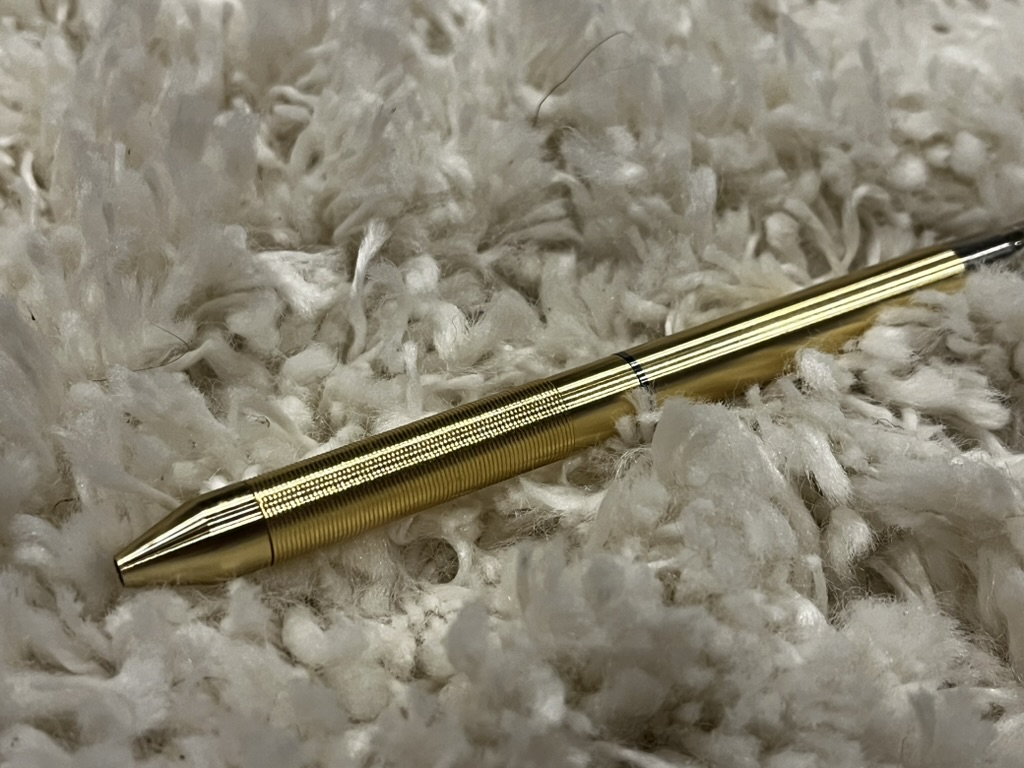 A Brass pencil laying on a plush white rug