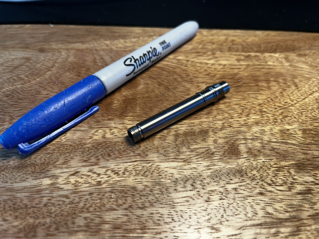 Shiny titanium part next to a blue sharpie